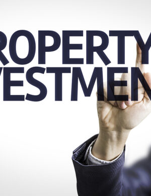 Business man pointing to transparent board with text: Property Investment